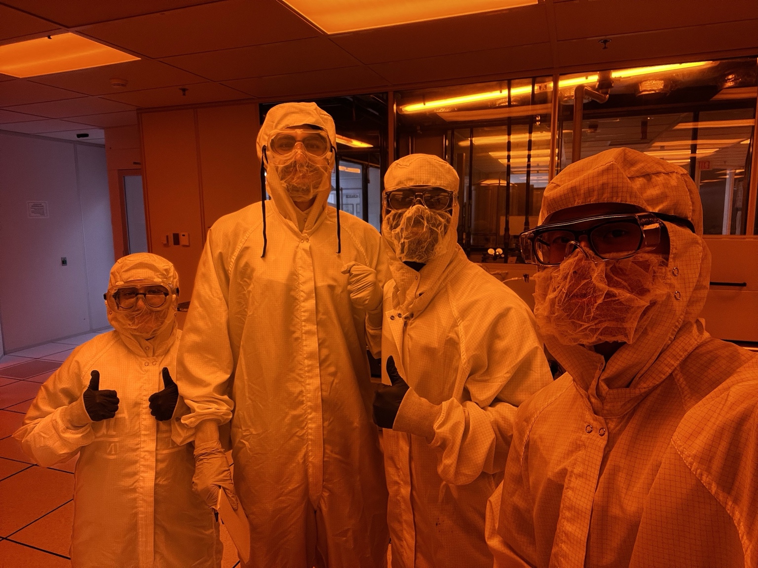 Four members of the cleanroom lab team wearing protective suits and goggles